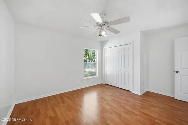 an empty room with wooden floor fan and windows