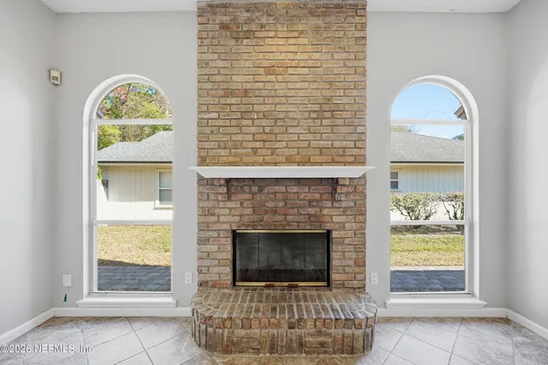a view of an empty room with chandelier fan and fireplace