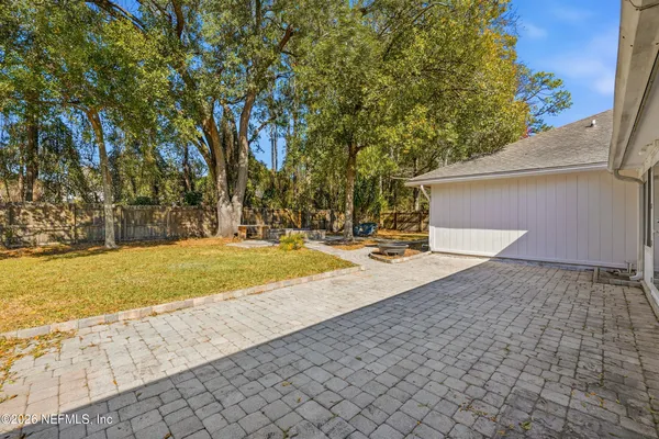a backyard of a house with large trees and outdoor seating