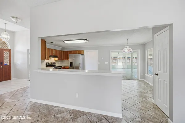 a living room with stainless steel appliances kitchen island granite countertop a refrigerator and cabinets