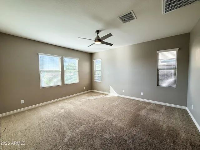 an empty room with windows and ceiling fan