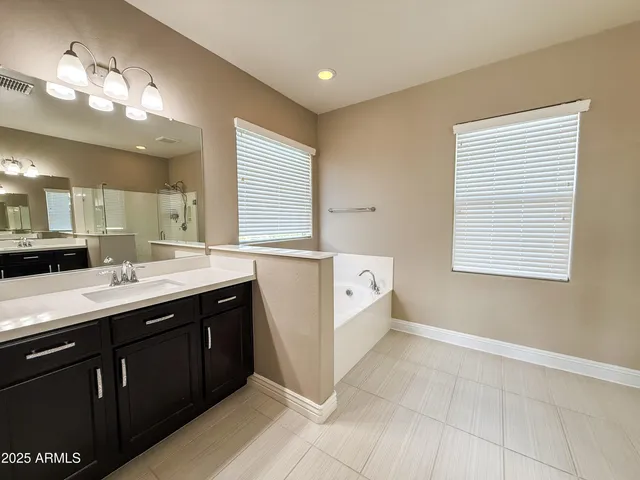 a spacious bathroom with a double vanity sink a mirror and a bathtub