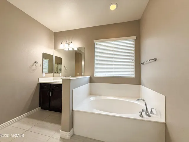 a bathroom with a bathtub a double vanity sink and mirror