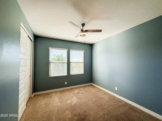 an empty room with a window and a ceiling fan