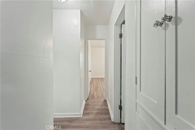 a view of a hallway with wooden floor and closet area