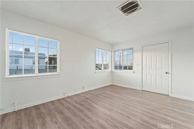a view of empty room with wooden floor and window