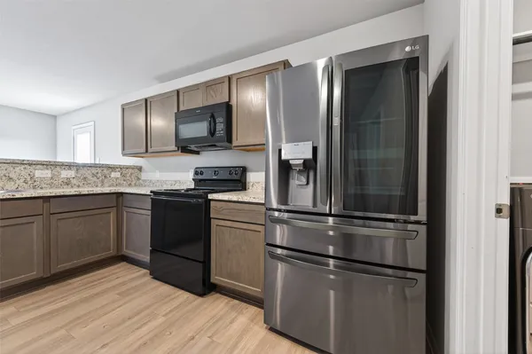 a kitchen with kitchen island granite countertop stainless steel appliances and wooden cabinets