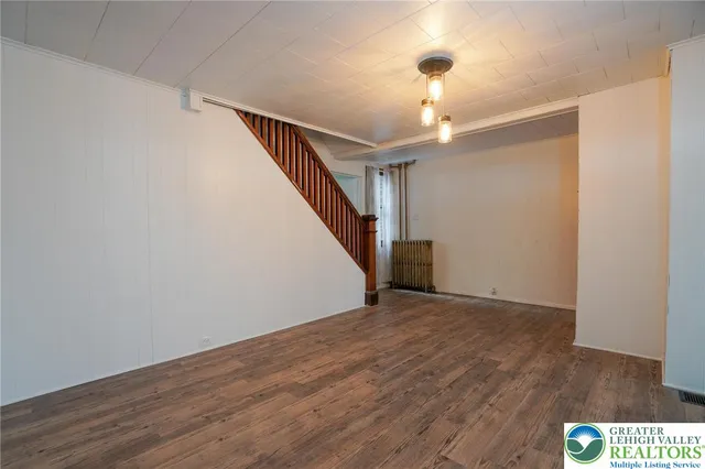 a view of an empty room with window and wooden floor