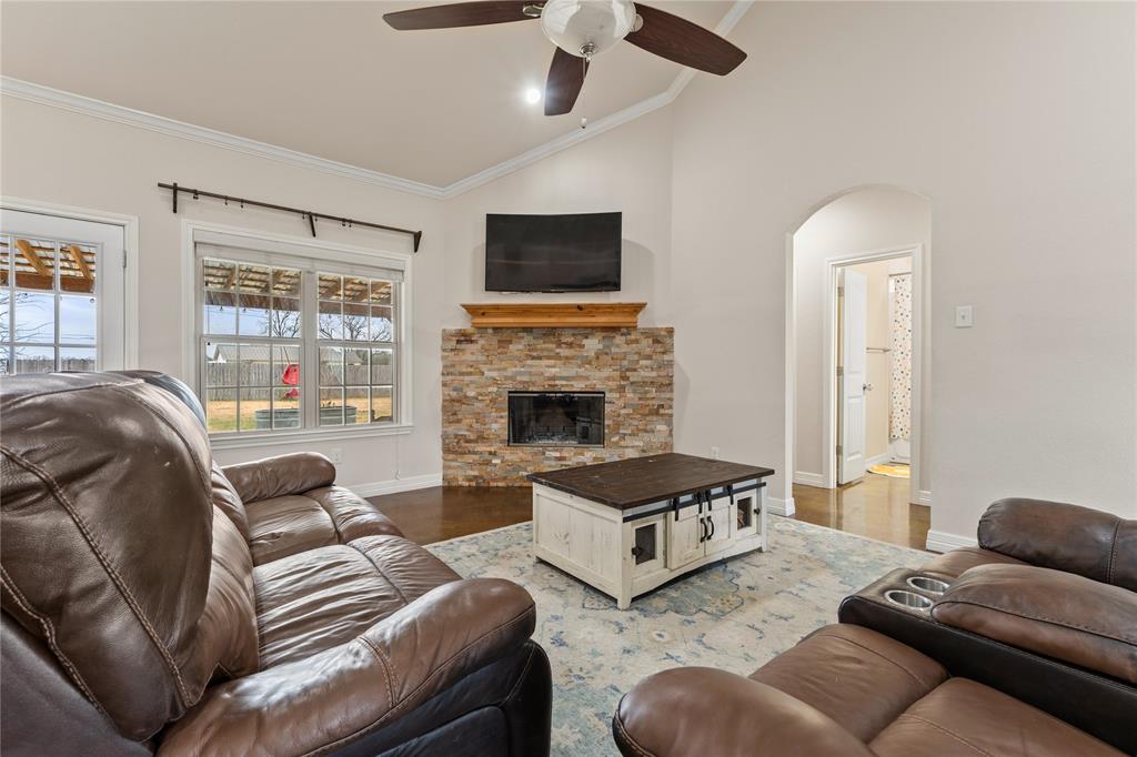 10514 Mesa Drive Waco, TX 76708 - Photo 11 of 37 Living room featuring ornamental molding, wood finished floors, a ceiling fan, a stone fireplace, and high vaulted ceiling