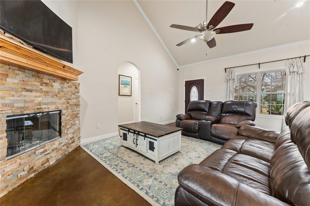 10514 Mesa Drive Waco, TX 76708 - Photo 14 of 39 Living room featuring high vaulted ceiling, concrete floors, crown molding, a stone fireplace, and arched walkways