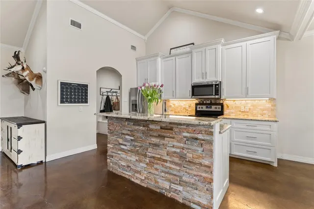 a kitchen with granite countertop a stove a sink and a microwave