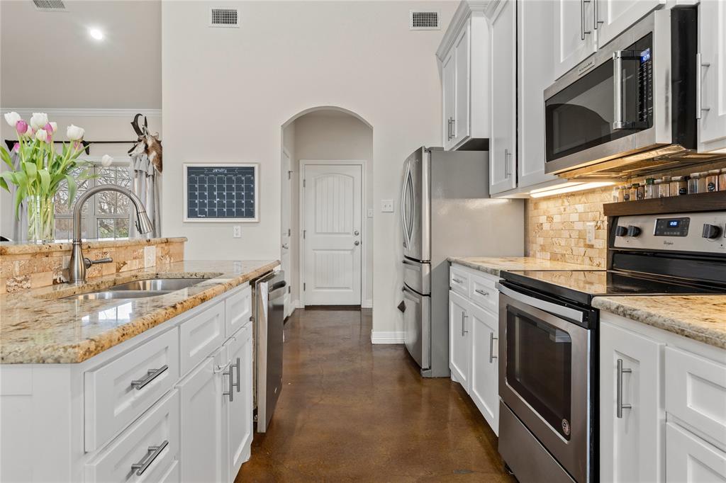 10514 Mesa Drive Waco, TX 76708 - Photo 18 of 39 Kitchen featuring appliances with stainless steel finishes, concrete flooring, light stone countertops, and white cabinets