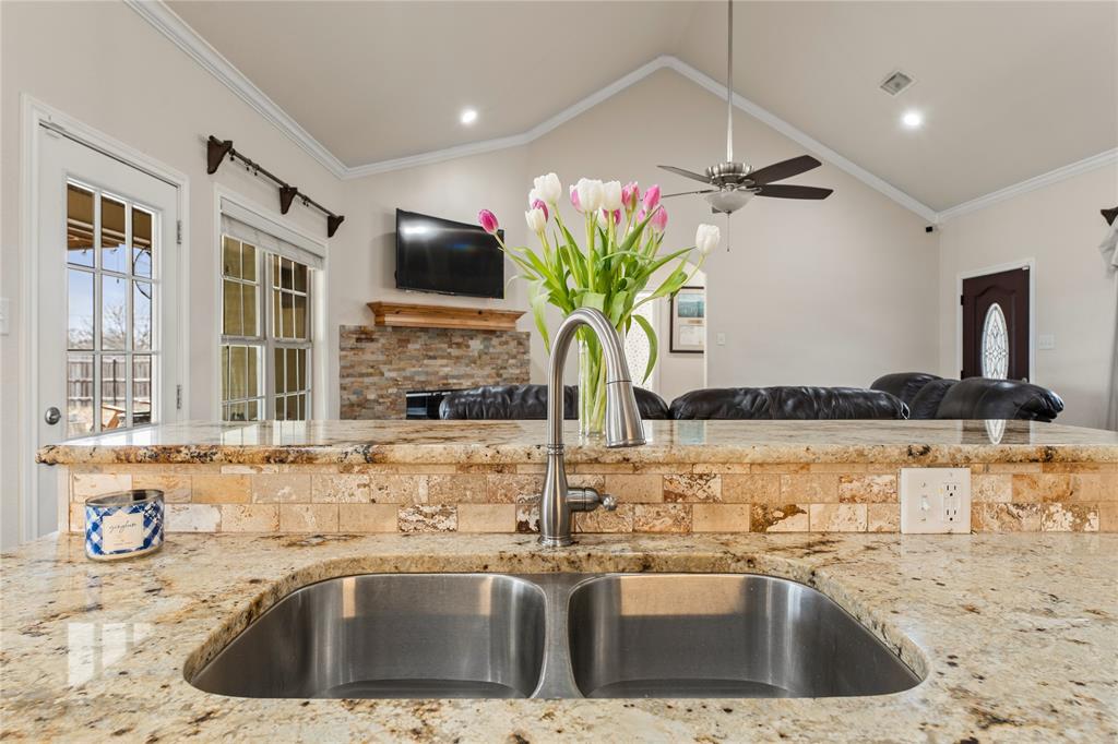 10514 Mesa Drive Waco, TX 76708 - Photo 38 of 39 Kitchen with light stone countertops, crown molding, open floor plan, a fireplace, and vaulted ceiling