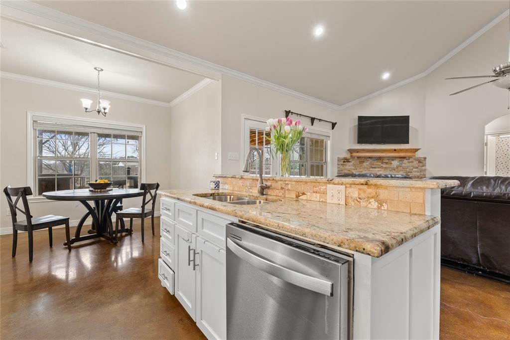 10514 Mesa Drive Waco, TX 76708 - Photo 19 of 39 Kitchen featuring white cabinets, finished concrete floors, light stone countertops, crown molding, and lofted ceiling
