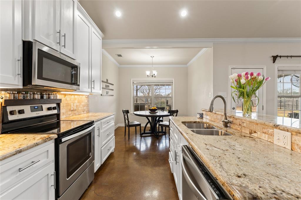 10514 Mesa Drive Waco, TX 76708 - Photo 20 of 39 Kitchen with stainless steel appliances, light stone countertops, concrete flooring, white cabinetry, and crown molding