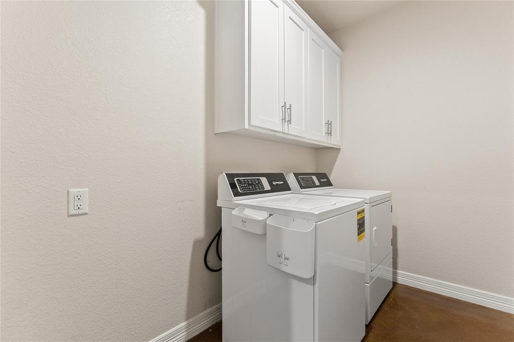 10514 Mesa Drive Waco, TX 76708 - Photo 25 of 37 Laundry room with washer and clothes dryer, cabinet space, finished concrete flooring, and a textured wall