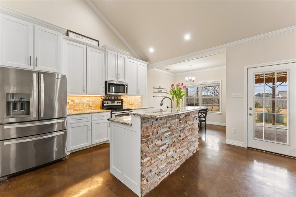 10514 Mesa Drive Waco, TX 76708 - Photo 3 of 39 Kitchen with appliances with stainless steel finishes, lofted ceiling, finished concrete floors, white cabinets, and light stone counters