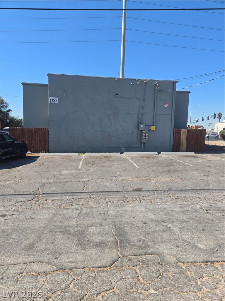1388 East Desert Inn Road, Unit 2 Las Vegas, NV 89169 - Photo 23 of 23 The structure's unadorned side wall is set against a clear blue sky, with a weathered asphalt parking area in the foreground.