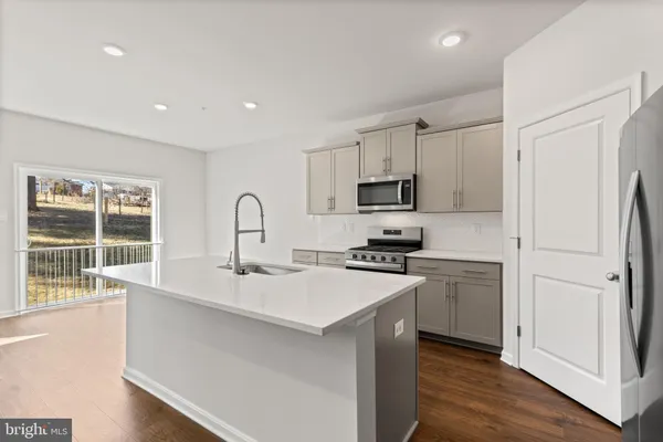 a kitchen with a sink a stove a refrigerator cabinets and a wooden floor