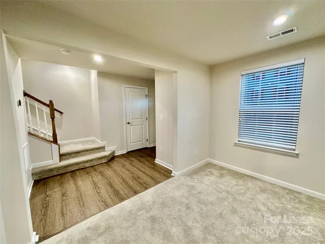 a view of an empty room with window and stairs
