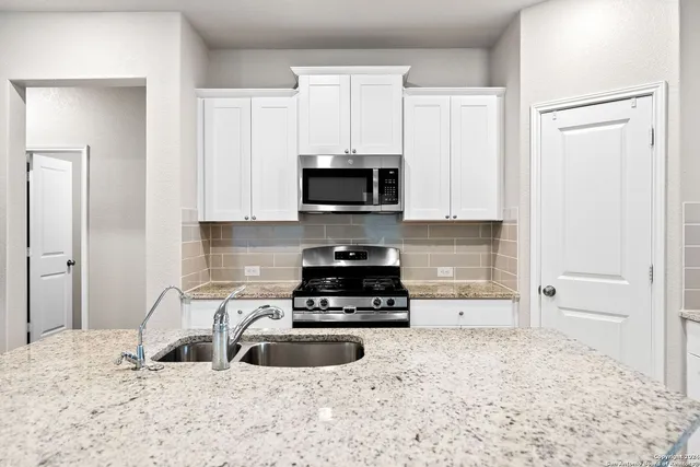 a kitchen with stainless steel appliances granite countertop white cabinets and a stove