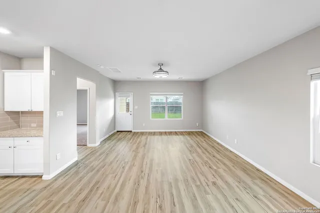 an empty room with wooden floor and windows