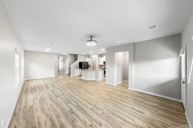 a kitchen with stainless steel appliances granite countertop a refrigerator a sink dishwasher a stove and a wooden floors