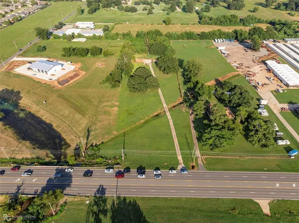an aerial view of a residential houses with outdoor space and trees all around
