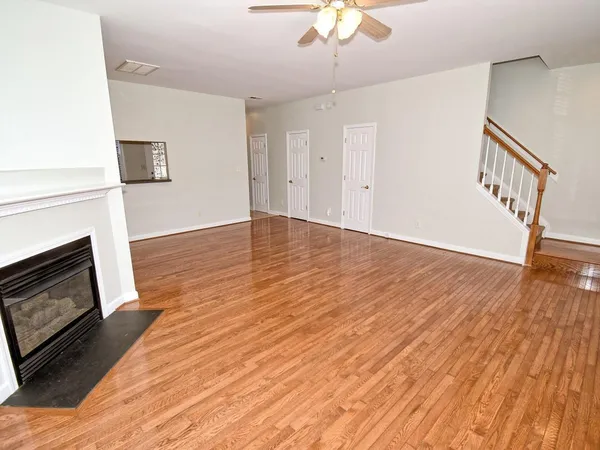 a view of an empty room with wooden floor fireplace and a window