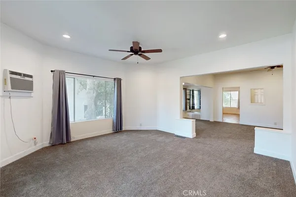 an empty room with chandelier fan and windows