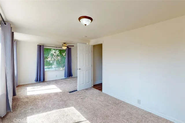 an empty room with a chandelier fan and windows