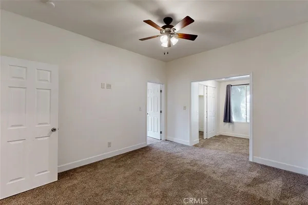 an empty room with windows and ceiling fan