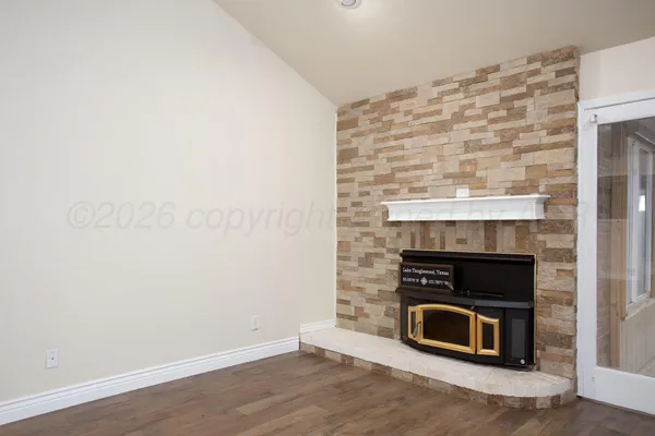 a view of an empty room with wooden floor fireplace and a window