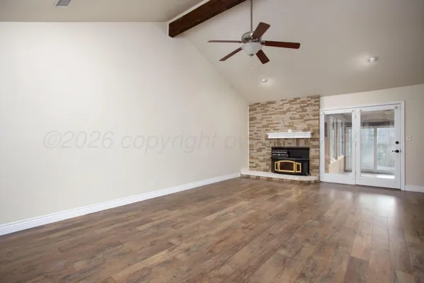 an empty room with wooden floor fireplace and a ceiling fan