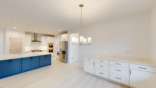 a kitchen with stainless steel appliances kitchen island granite countertop a sink dishwasher a refrigerator and white cabinets with wooden floor