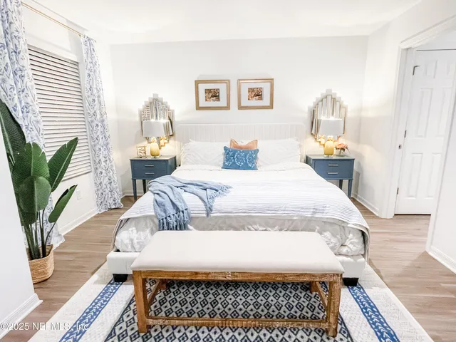 a large bedroom with a bed a rug and wooden floor