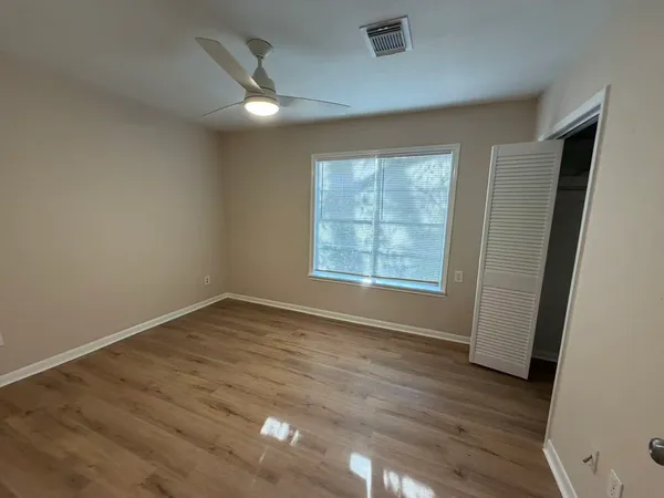 an empty room with wooden floor and windows