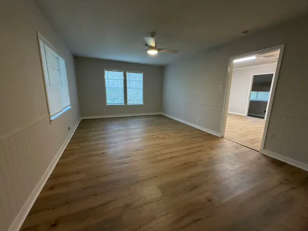 an empty room with wooden floor and windows