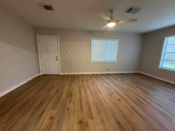 an empty room with wooden floor and windows