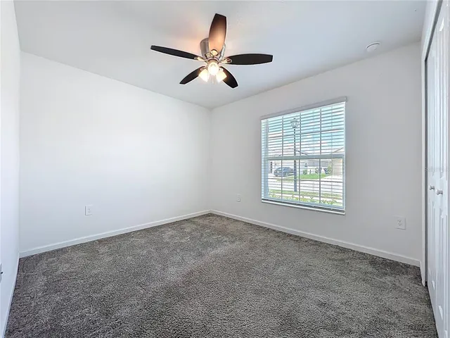 an empty room with ceiling fan and window