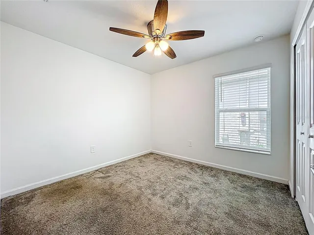 an empty room with windows and fan