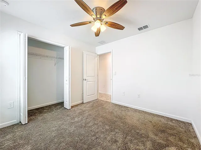 an empty room with closet and a chandelier fan