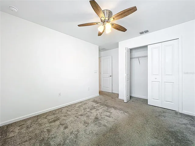 an empty room with a ceiling fan and a window