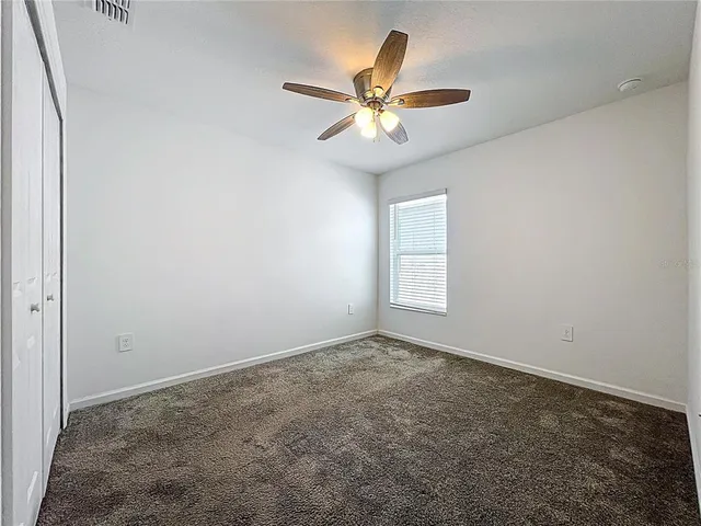 an empty room with a window and a fan