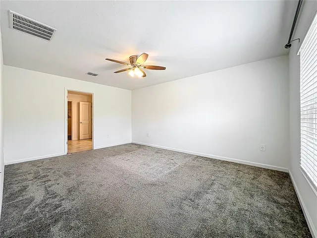 an empty room with windows and chandelier fan