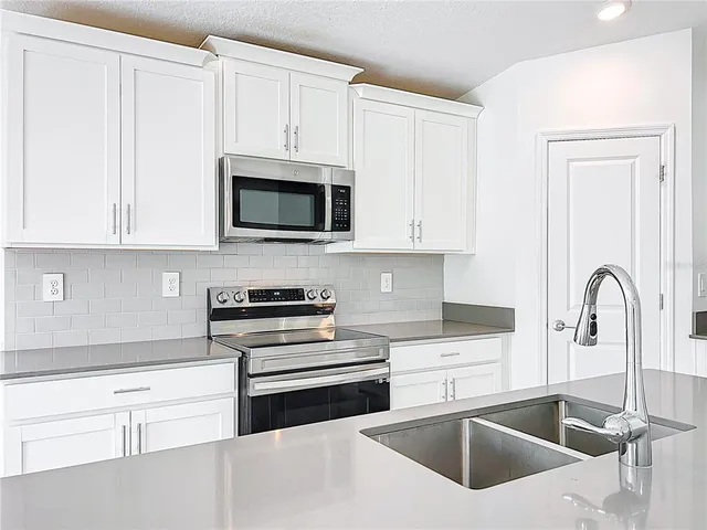 a kitchen with granite countertop white cabinets and white appliances