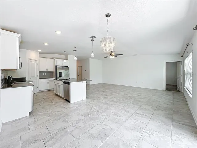 a view of a kitchen with kitchen island stainless steel appliances cabinets a sink and a chandelier