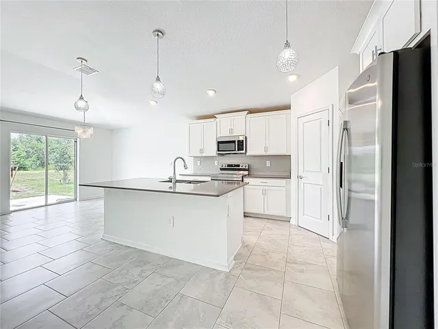 a kitchen with white cabinets and refrigerator