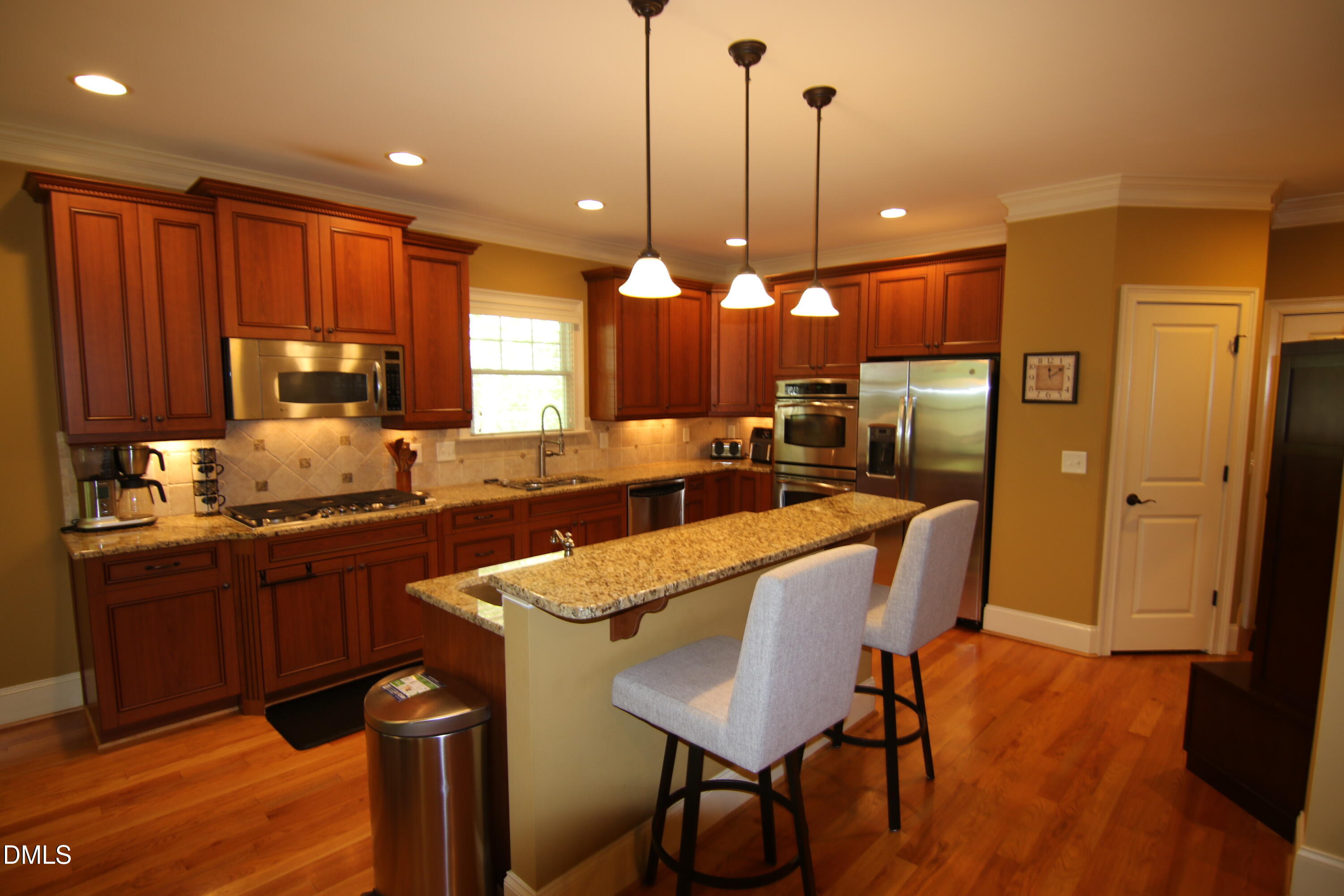 8104 Henderson Road Apex, NC 27539 - Photo 12 of 45 a kitchen with granite countertop wooden floors cabinets a sink and chairs