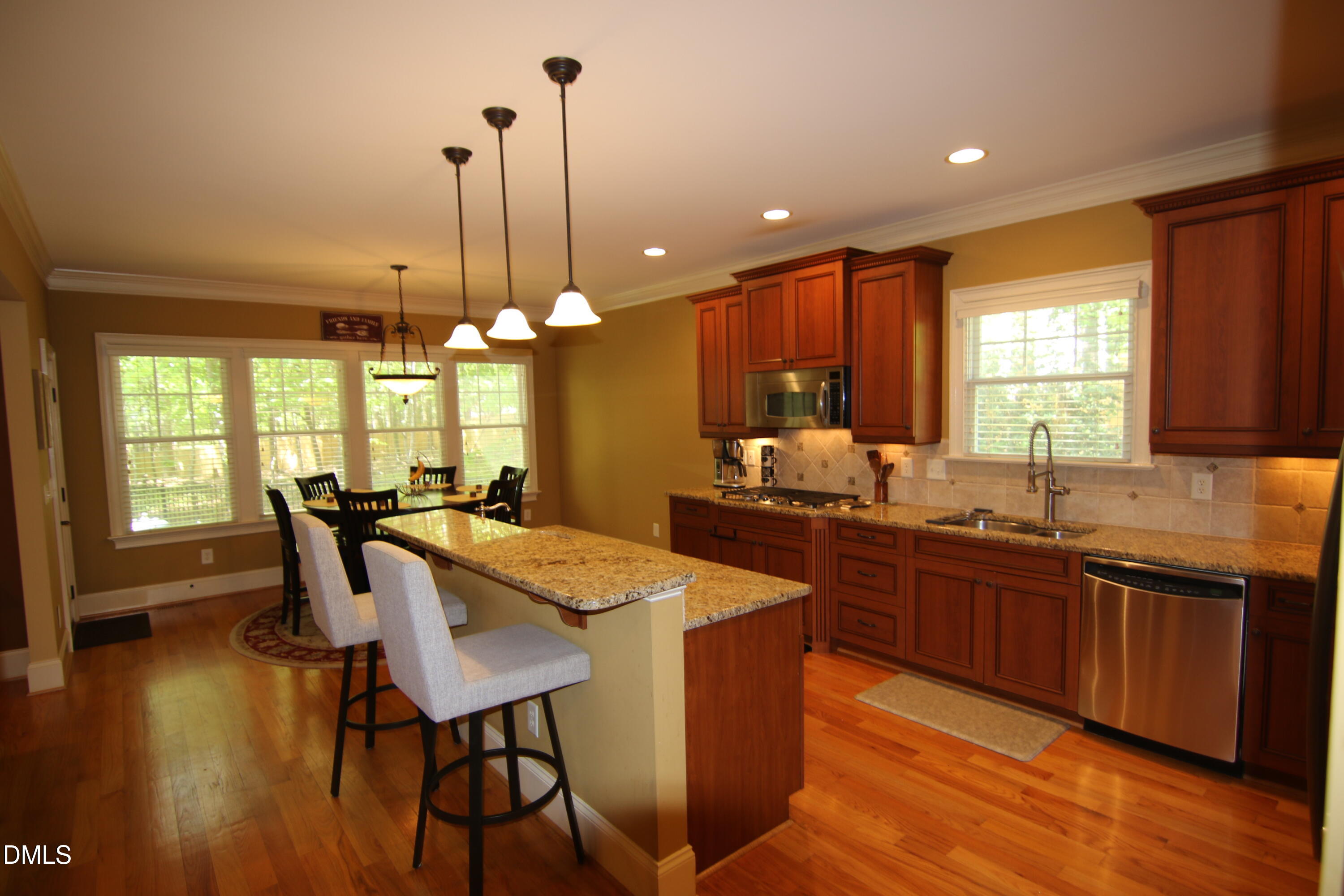 8104 Henderson Road Apex, NC 27539 - Photo 13 of 45 a kitchen with stainless steel appliances granite countertop wooden floor dining table and chairs